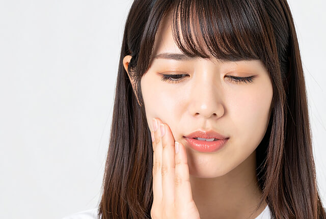 歯の痛みを感じて頬を手で押さえている女性
